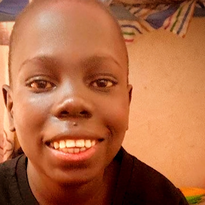 Lwanga Sillaje smiling, in a black sweater with a red and blue diamond pattern